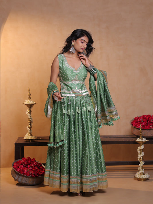 Front full-length view of a model wearing a pista green printed cotton chaniyacholi set featuring a flared skirt with tiered borders, sleeveless peplum-style embroidered bodice, and matching draped dupatta for Navratri festive celebrations.